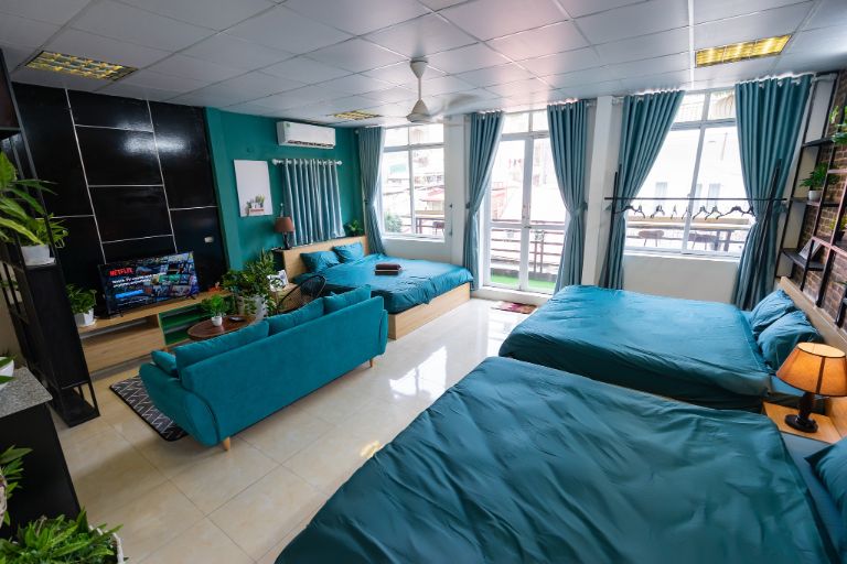 Phòng 3 giường đôi nổi bật với màu xanh đặc trưng với view cửa sổ nhìn ra thành phố