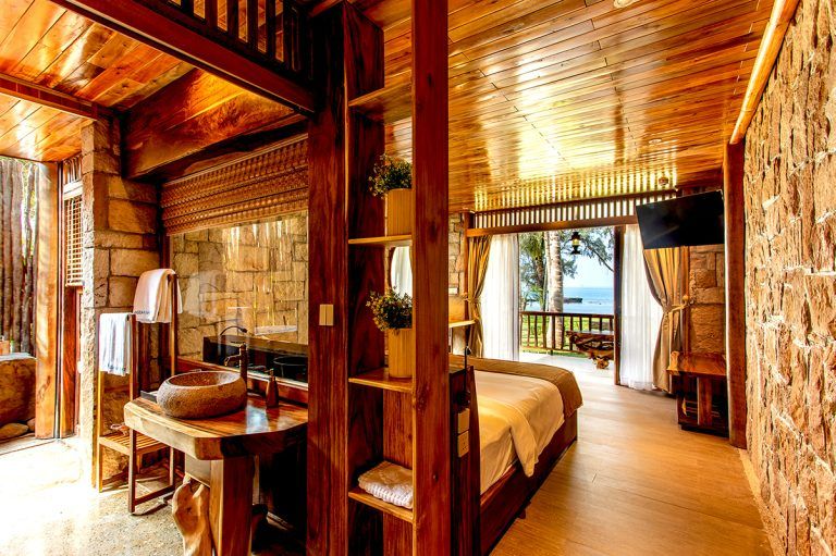 Phòng ngủ của Ocean Bay Resort & Spa Phú Quốc có thiết kế sàn và trần bằng gỗ ốp còn các mặt tường được dựng bằng đá lớn mang đến không gian nghỉ vừa mộc mạc, vừa hoang dã. (nguồn ảnh: oceanbayphuquoc)