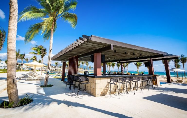 Khu vực quầy bar ngoài trời của Alma Resort nhận được rất nhiều sự yêu thích của khách du lịch với tầm nhìn hướng bể bơi và bãi biển cực chill. 