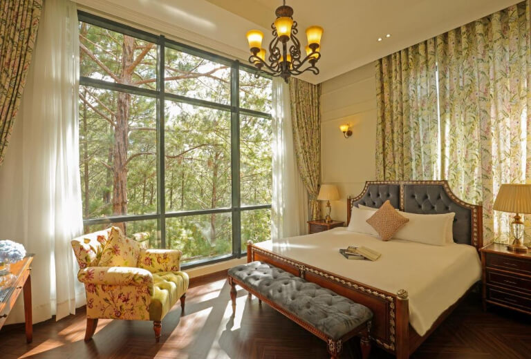 Phòng ngủ mang nét nghệ thuật Pháp với không gian mở nhìn ra vườn thông.