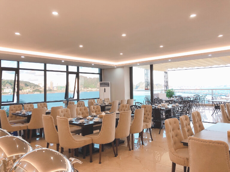 Không gian nhà hàng rộng với tone màu be và thiết kế mở hướng biển, mang lại sự thoáng đãng.