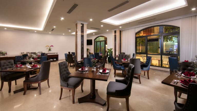 Nhà hàng sử dụng bàn ghế gỗ màu sậm đối lập với nền tường sáng, mang lại không gian ẩm thực sáng sủa.