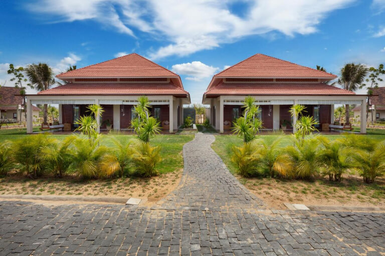 Căn biệt thự nổi bật với thiết kế mái ngói đỏ, được bao quanh bởi các thảm cỏ xanh.