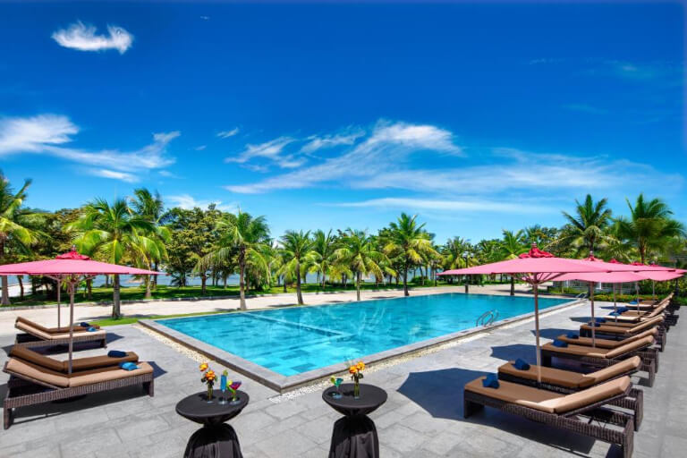 Bể bơi ngoài trời có tầm nhìn đẹp, được bao quanh bởi các rặng dừa xanh.