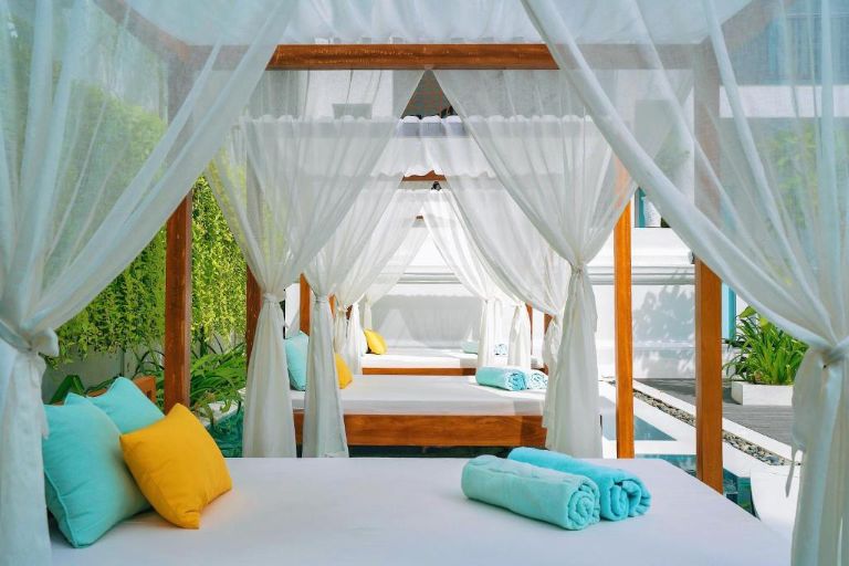Bể bơi ngoài trời được bao quanh là các rặng cây và những chiếc giường được decor với màn buông cổ phong siêu chill. 
