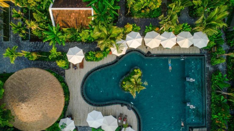 La Siesta Hoi An với bể bơi mang lối thiết kế độc lạ khơi nguồn từ những con sóng uốn lượn, bao quanh là cây xanh và ô che nắng.