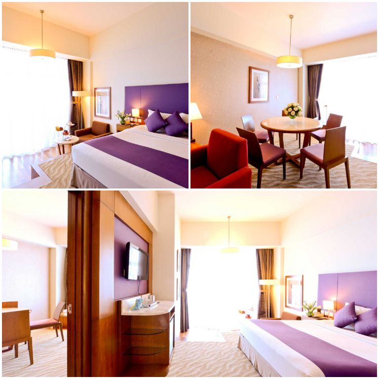 Phòng suite sở hữu một phòng khách rộng với bộ sofa đỏ sang chảnh, cùng với hệ thống cửa kính cách nhiệt cao cấp. 