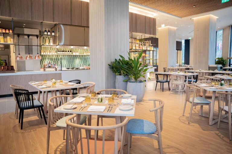 Nhà hàng được bố trí hệ thống bàn ghế sáng màu đồng kiểu thiết kế tươi trẻ chung.