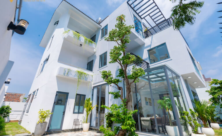 Happier Villa nổi bật với thiết kế hiện đại, kết hợp nhiều ô cửa kính xanh.