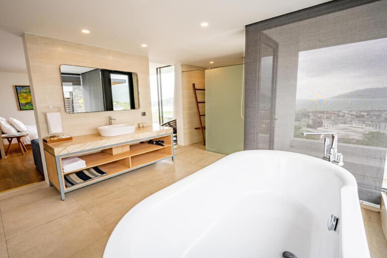 Phòng vệ sinh ấn tượng với bồn tắm lớn bên cạnh cửa sổ mở.
